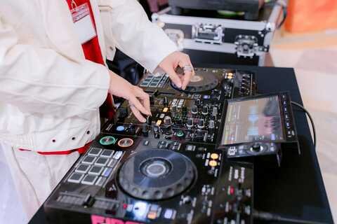 DJ mixing equipment and a person operating the turntables and controller in a studio or event setting.