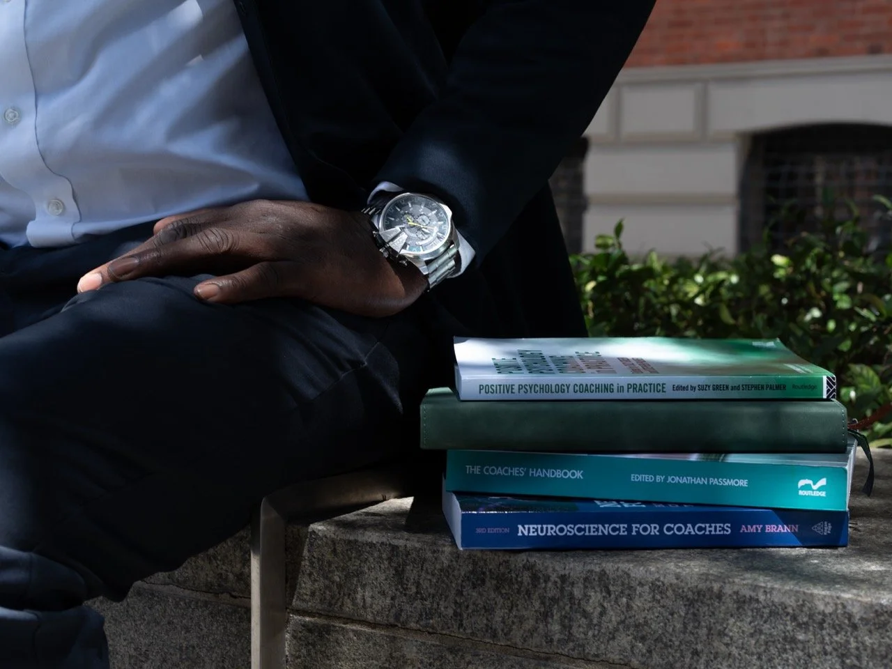 Image of a man sitting next to a pile of books.