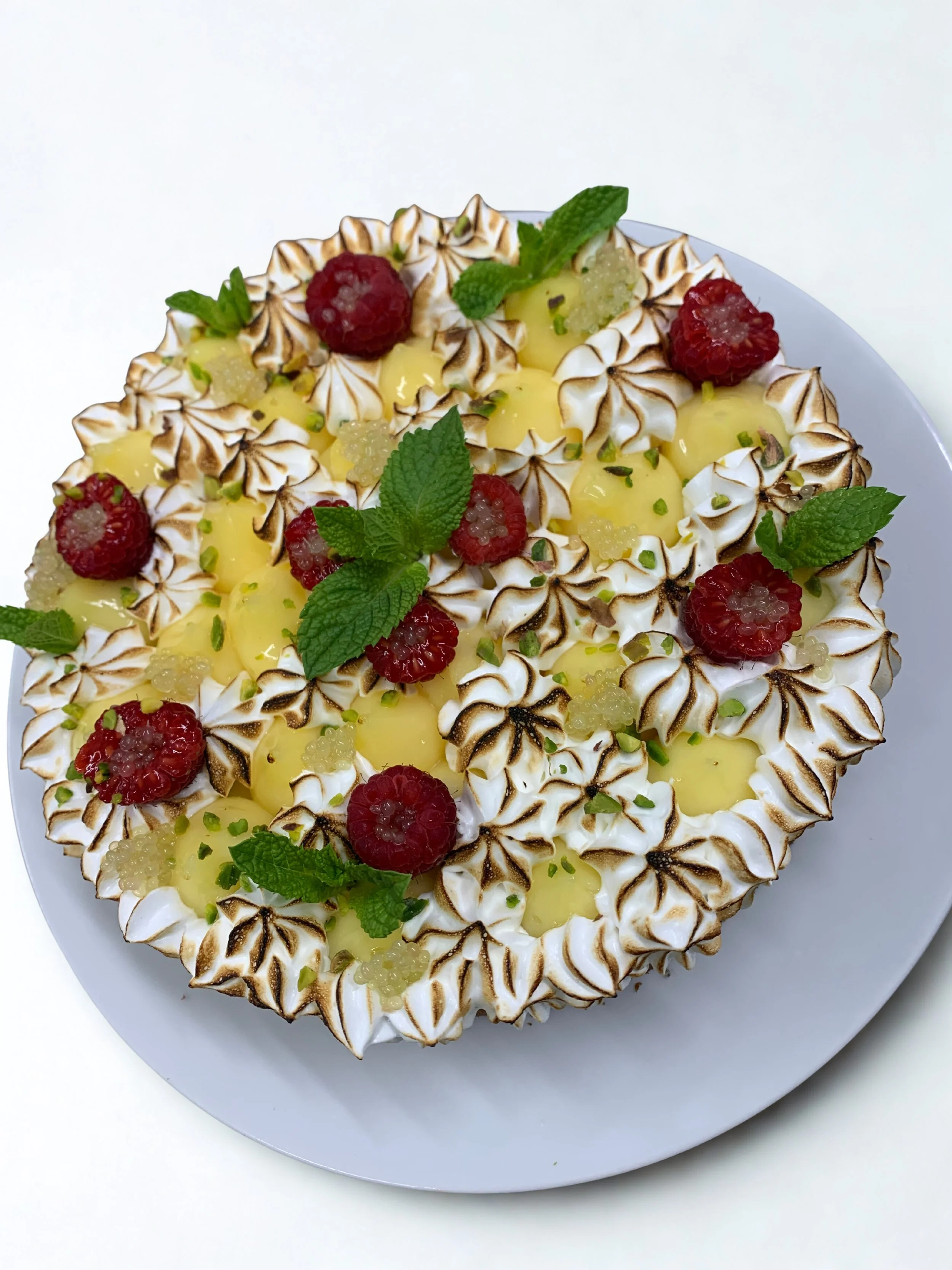 Gâteau décoré avec des mûres, des feuilles de menthe, et des meringues grillées.
