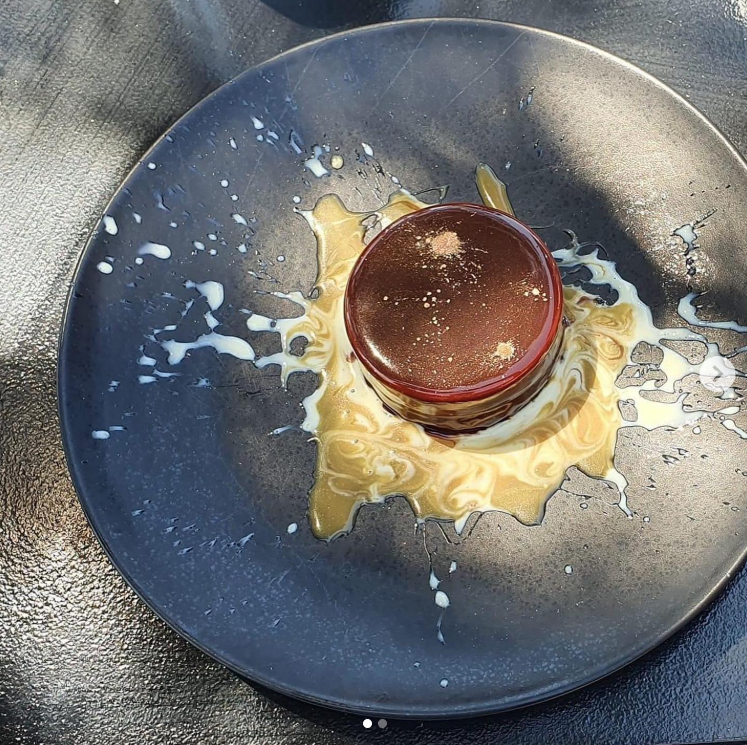 Une tasse de café ou de chocolat chaud renversée sur une assiette, avec des éclaboussures de liquide autour.