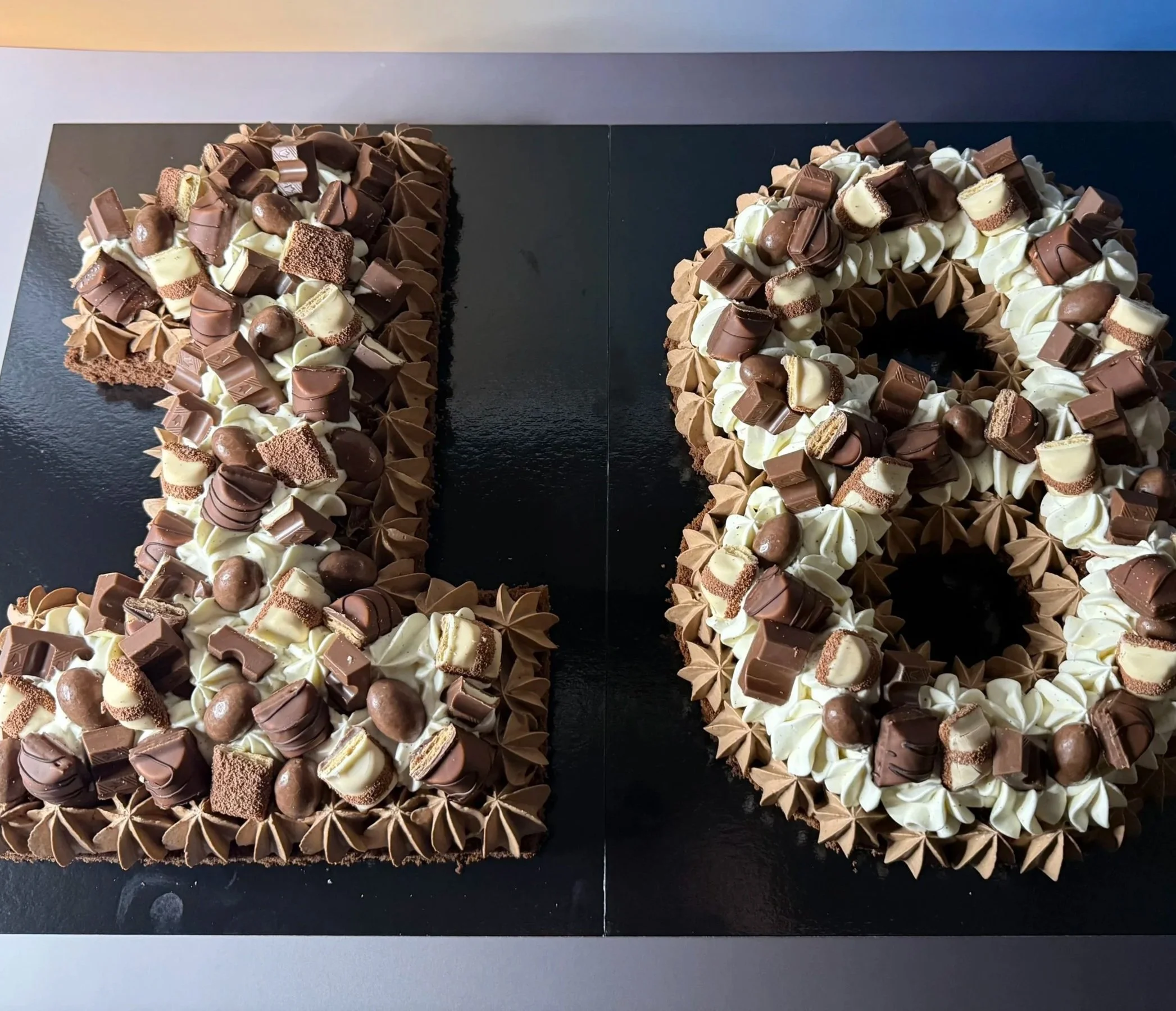 Gâteau number 18 formé par deux parties, décoré de chocolat, crème et biscuits.