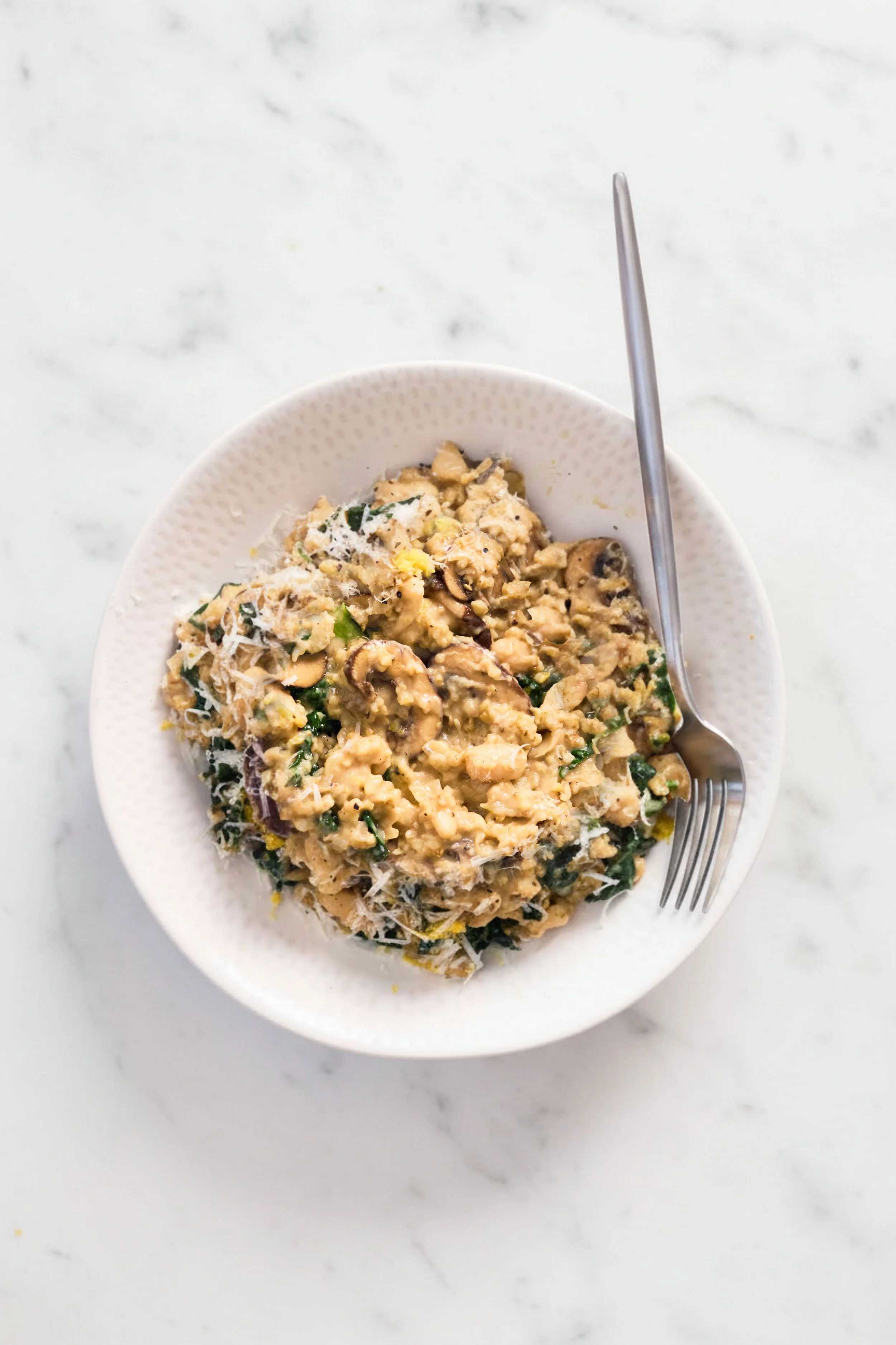 White plate filled with risotto on marble background