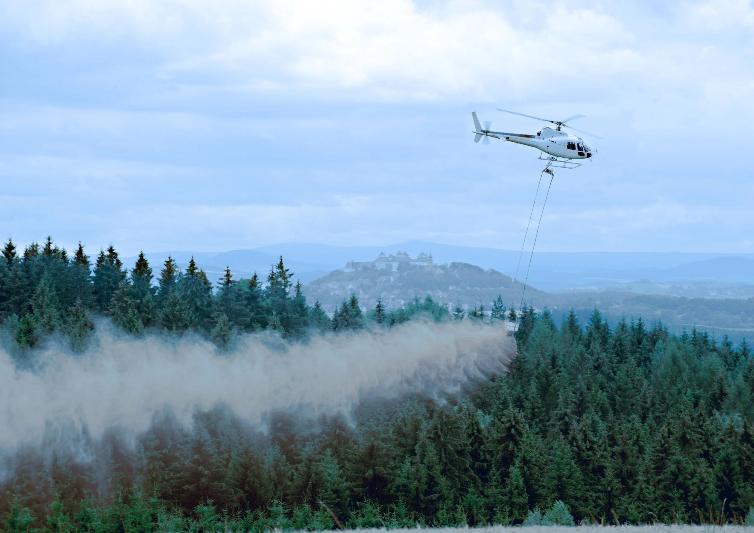 Hubschrauber sprüht pyrofasch im Wald bei einem Waldbrand.