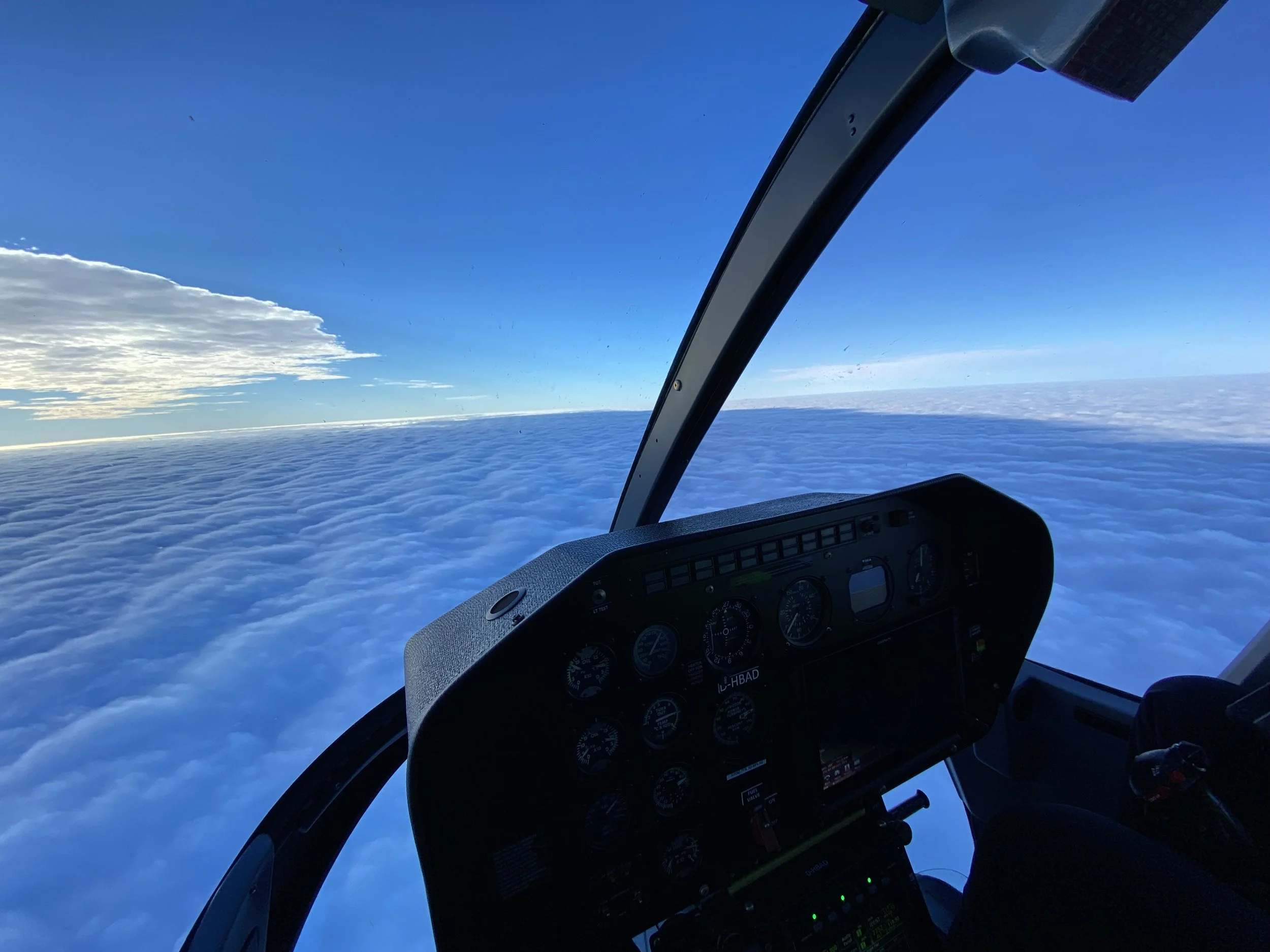 Cockpit eines Hubschraubers mit Blick auf Wolken und blauen Himmel