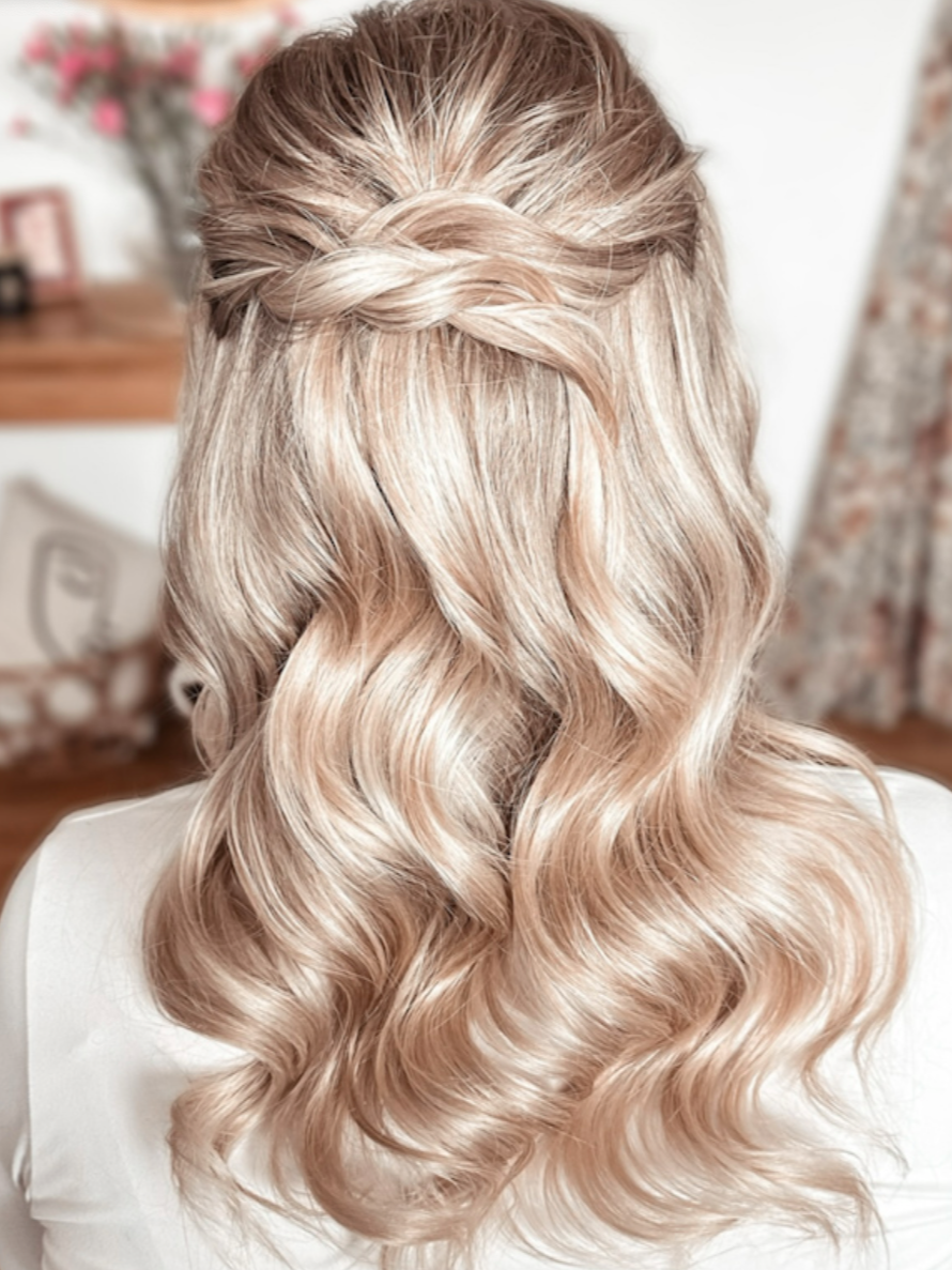 Back view of bridal hair, blonde, curly hair styled with a half-up braided crown. soft waves