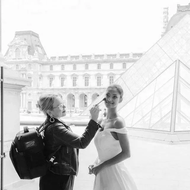 A woman applying makeup to a model near the Louvre Pyramid in Paris.