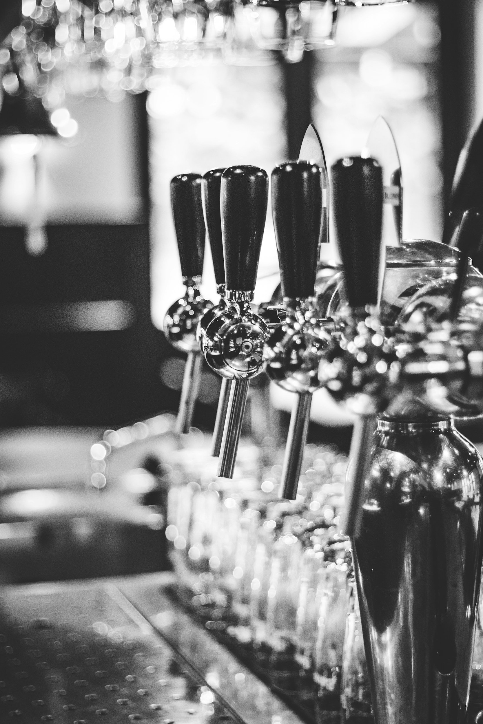 Black and white photo of beer tap handles lined up at a bar.
