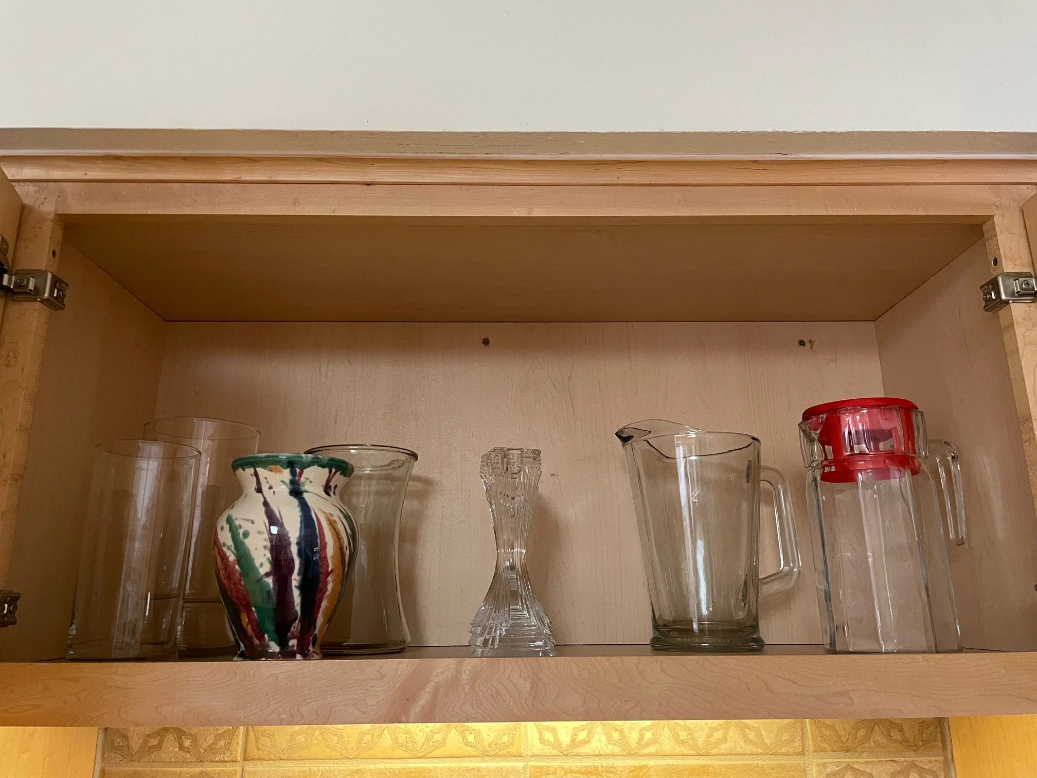 Kitchen shelf over sink with vases, pitchers, and candle sticks