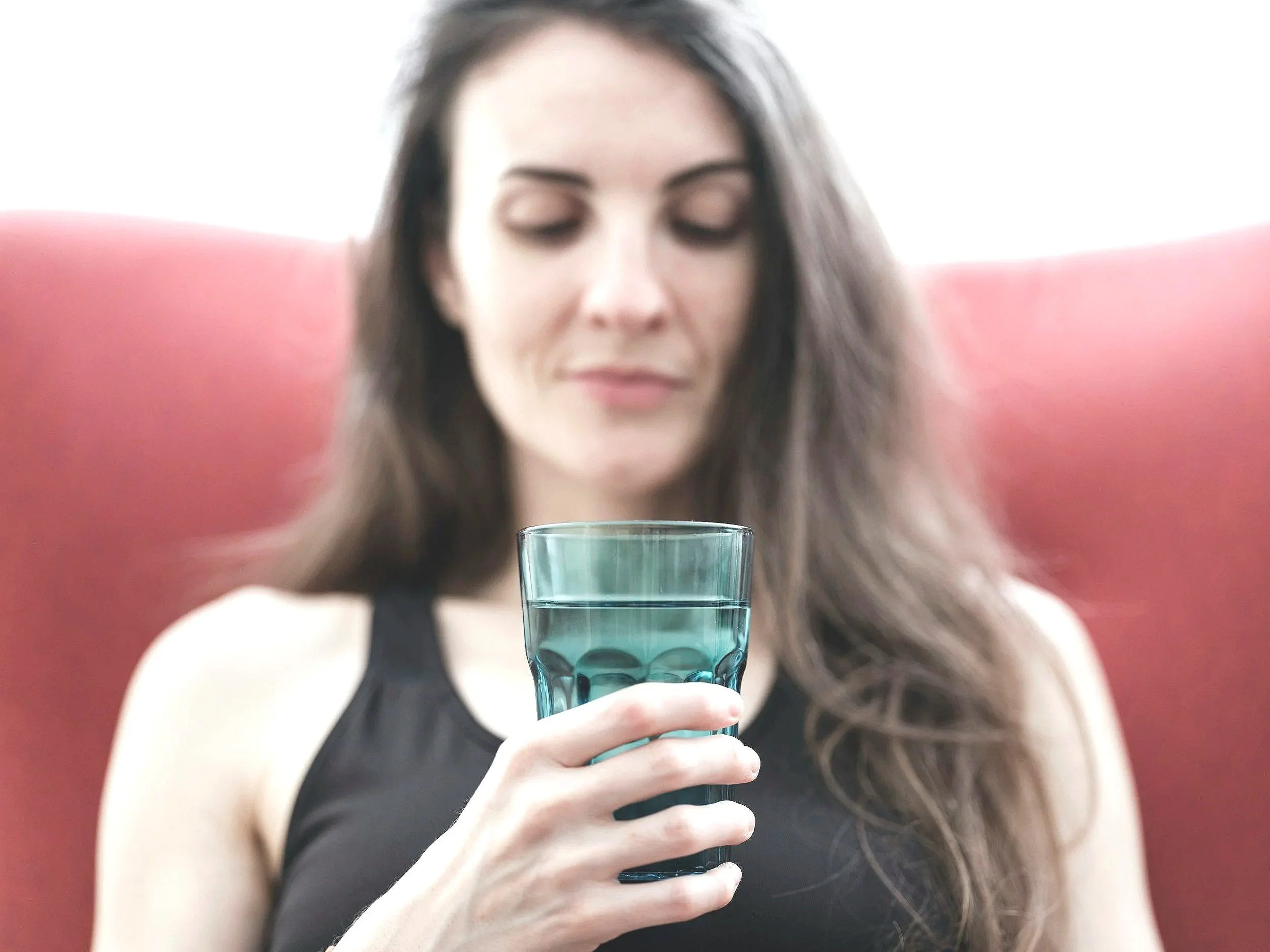 A woman holding a glass of water and wondering if her drinking water is clean and healthy.