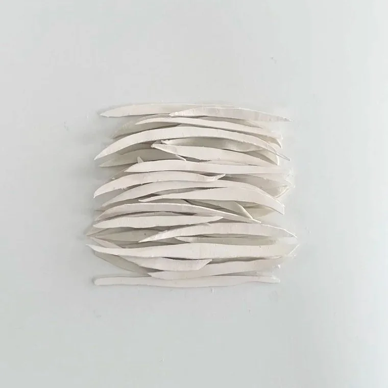 A minimalist wall art piece made of white paper strips arranged in a grid pattern.