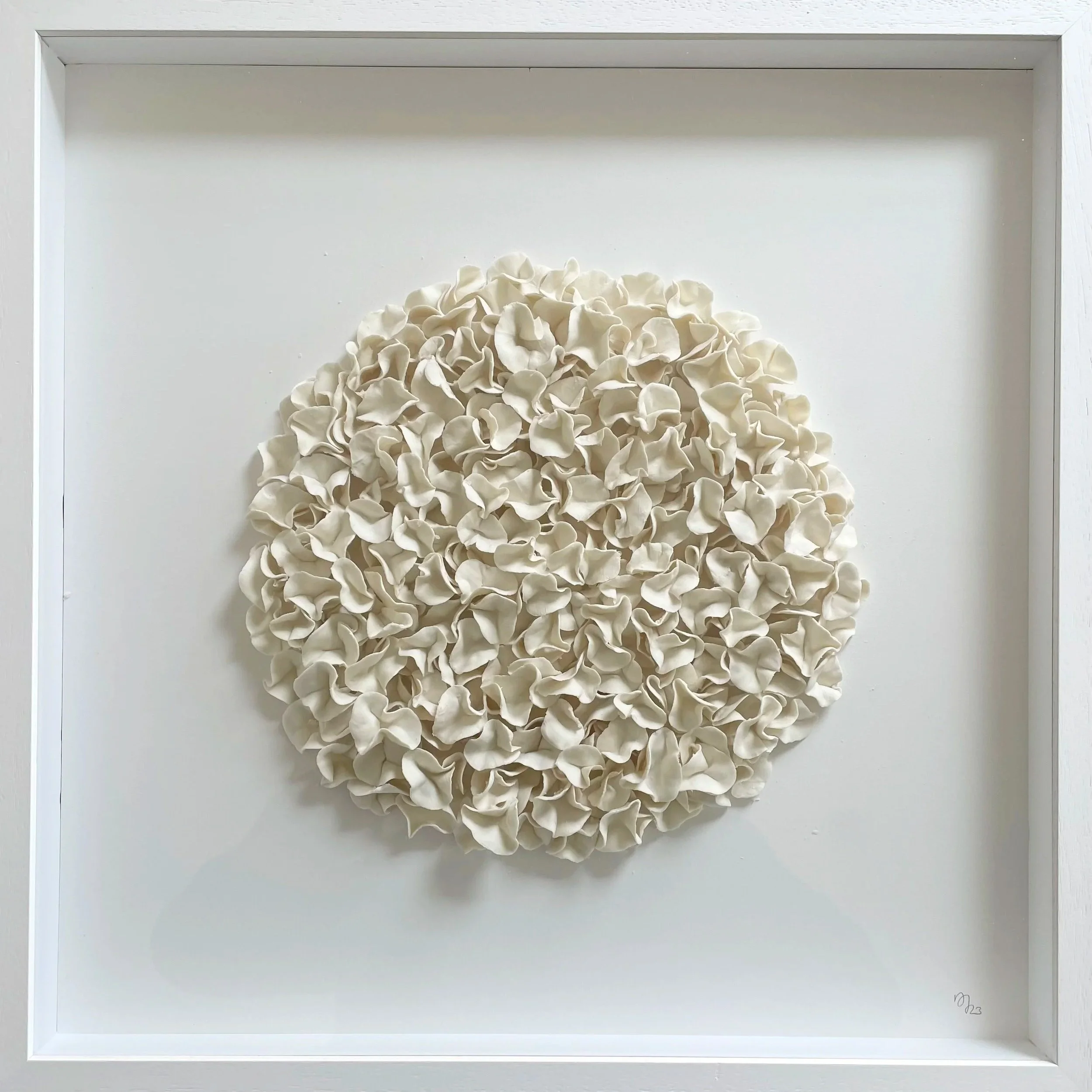 White floral arrangement in a white frame, arranged in a spherical shape.
