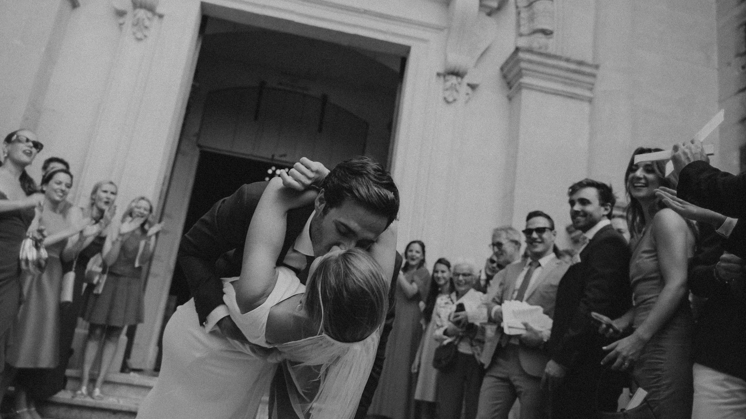 Un couple de mariés dansant lors de leur mariage entouré d'invités qui applaudissent et sourient, dans un lieu élégamment décoré.