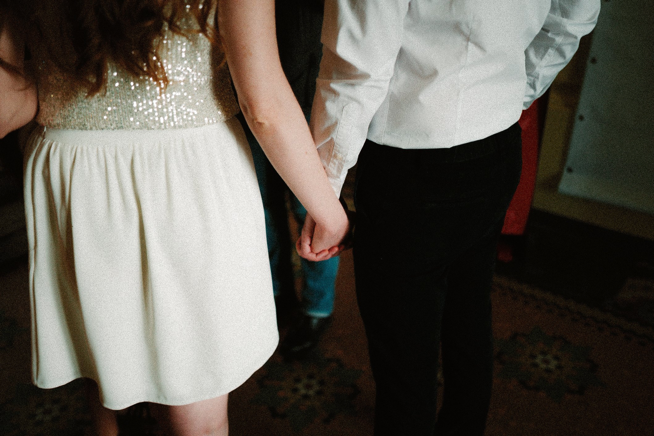 Deux personnes se tiennent la main lors d'une cérémonie ou d'un événement spécial, entourées d'autres personnes.
