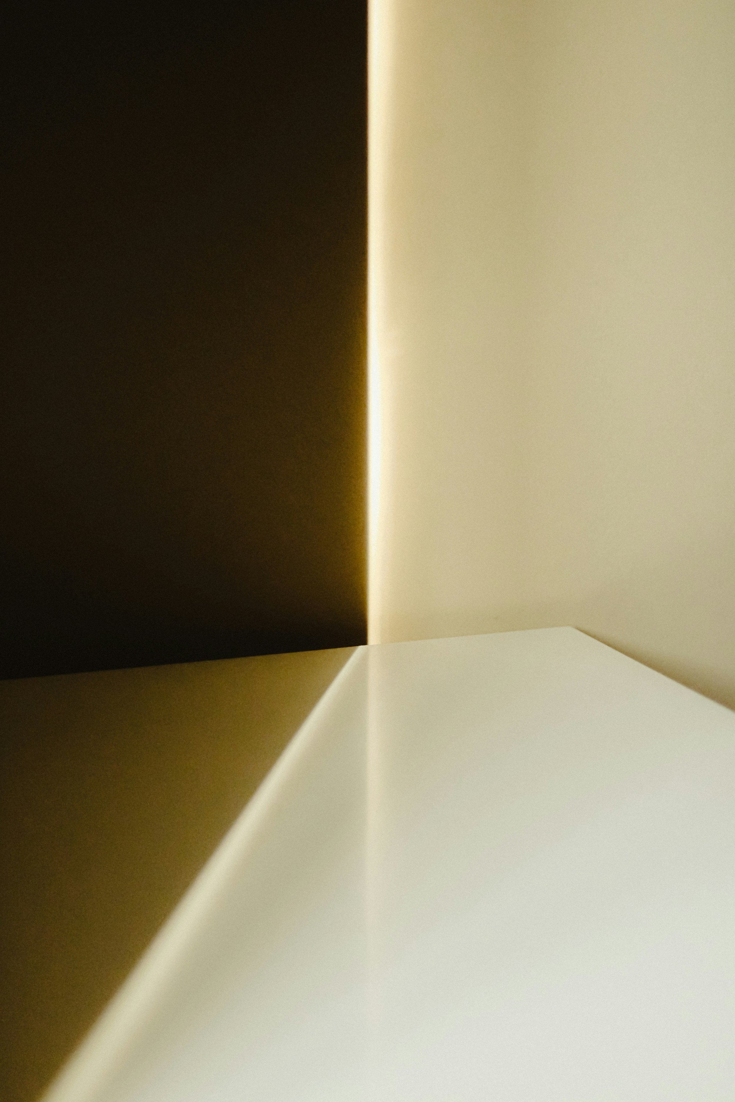 Nahaufnahme von Ecken und Kanten eines geometrischen Objekts mit schwarzen, weißen und beige Farbflächen, die durch Licht und Schatten hervorgehoben werden.