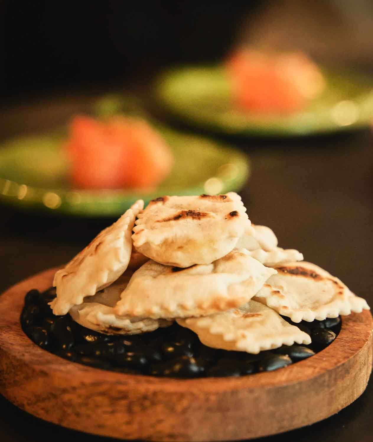 Tortelli alla lastra con salsiccia e patate su vassoio in legno design