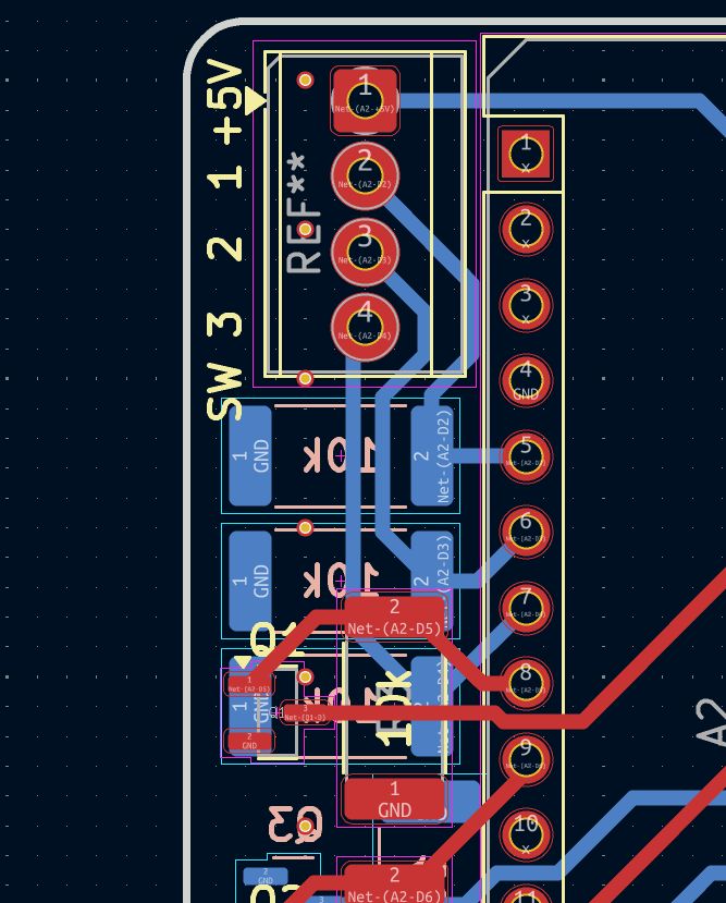 Close-up of an electronic circuit board with various red, blue, and purple components, labeled pins, and connecting traces.