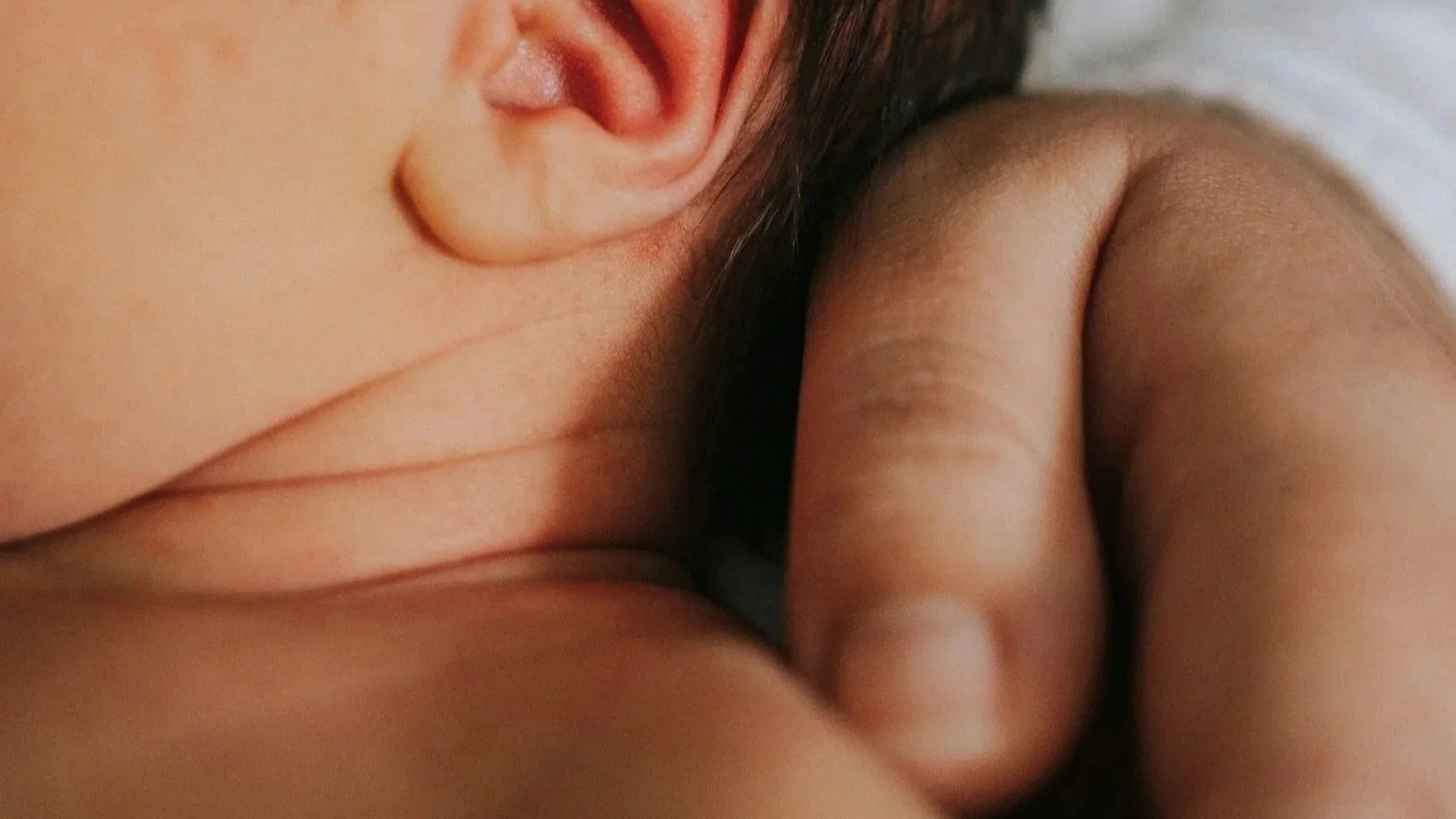 Close-up photo of a child's face and arm, showcasing soft skin and natural features.