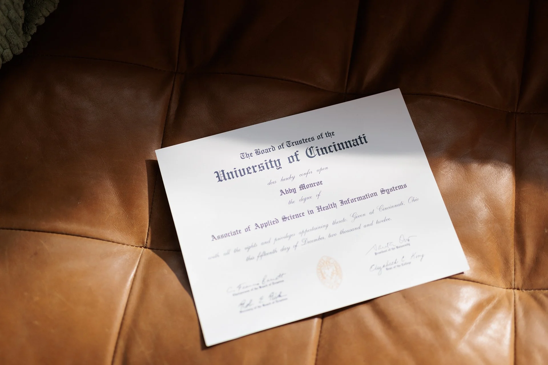 Graduation diploma from the University of Cincinnati lying on a brown leather couch.