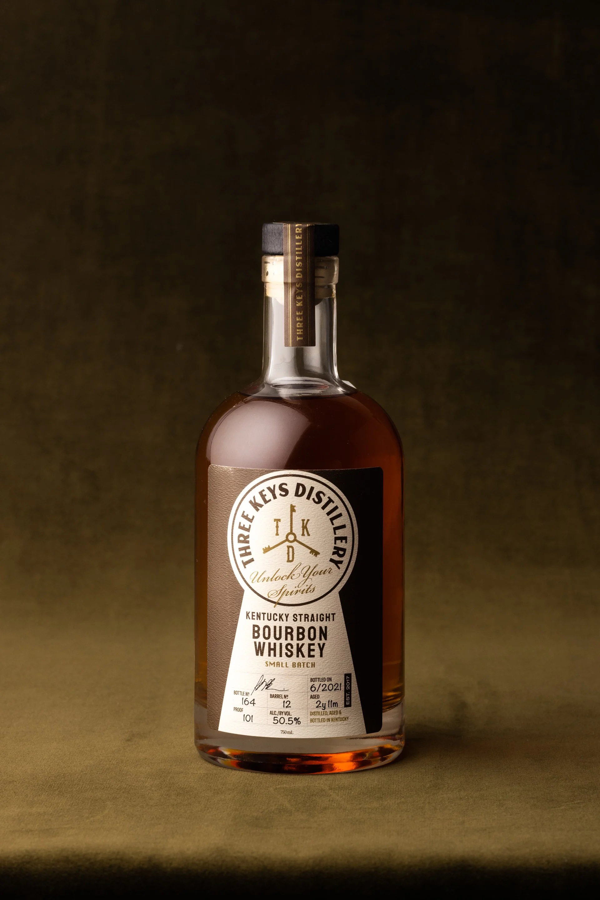 A bottle of Three Keys Distillery Kentucky Straight Bourbon Whiskey on a dark background.