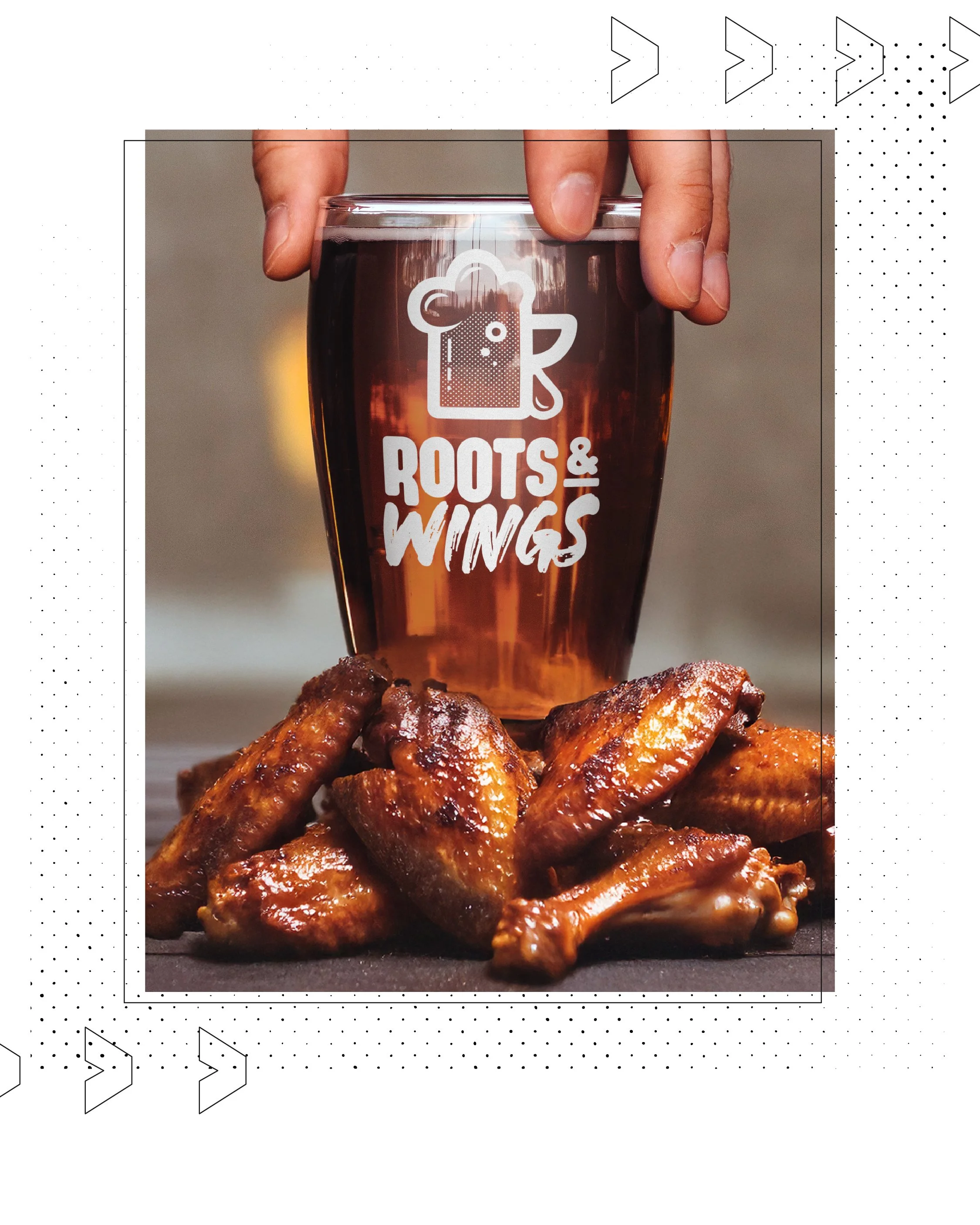 A hand holding a glass of beer with the logo 'Roots & Wings' on it, positioned behind a pile of glazed chicken wings.