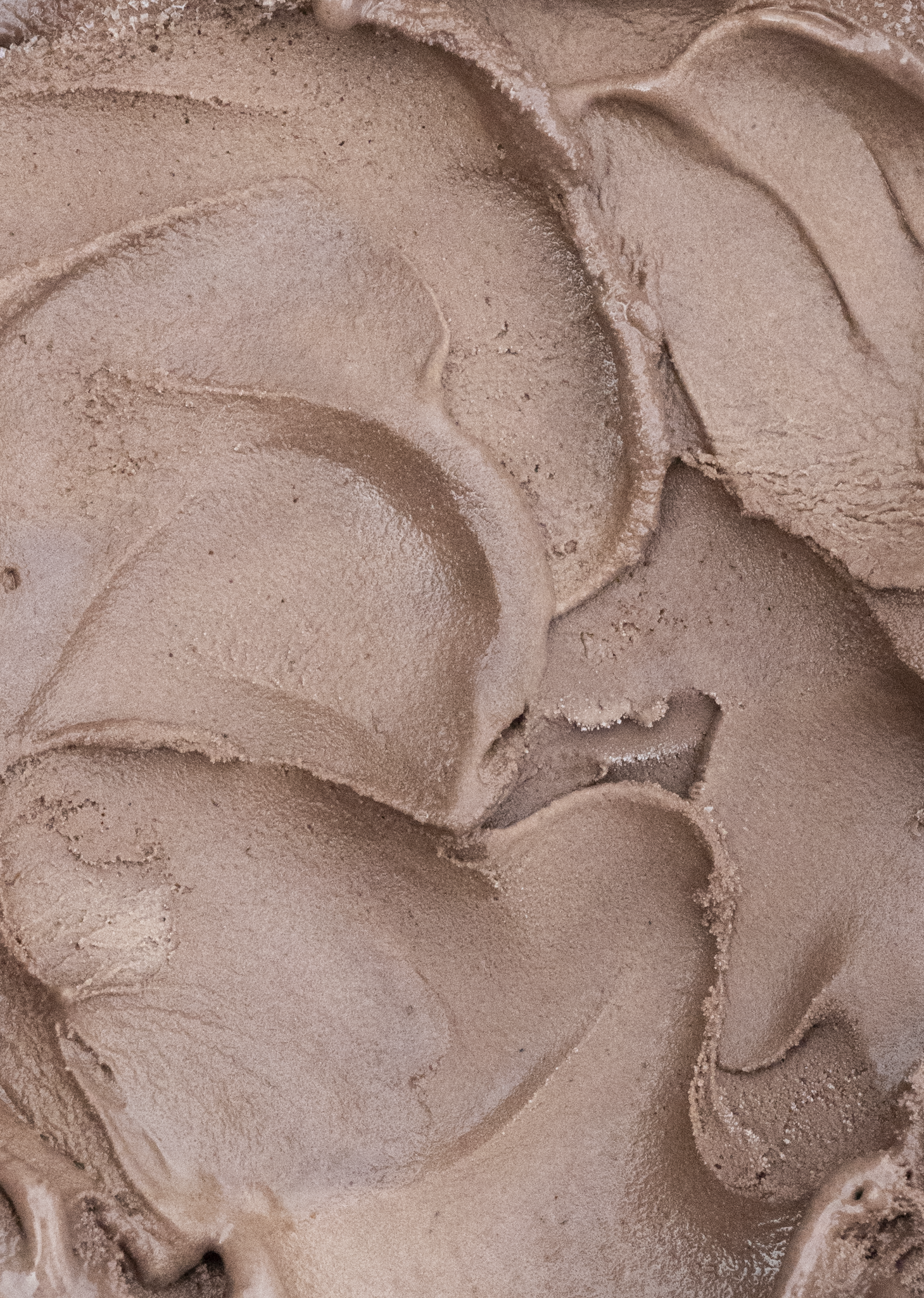 Close-up of brown ice cream swirled in a creamy, textured pattern.