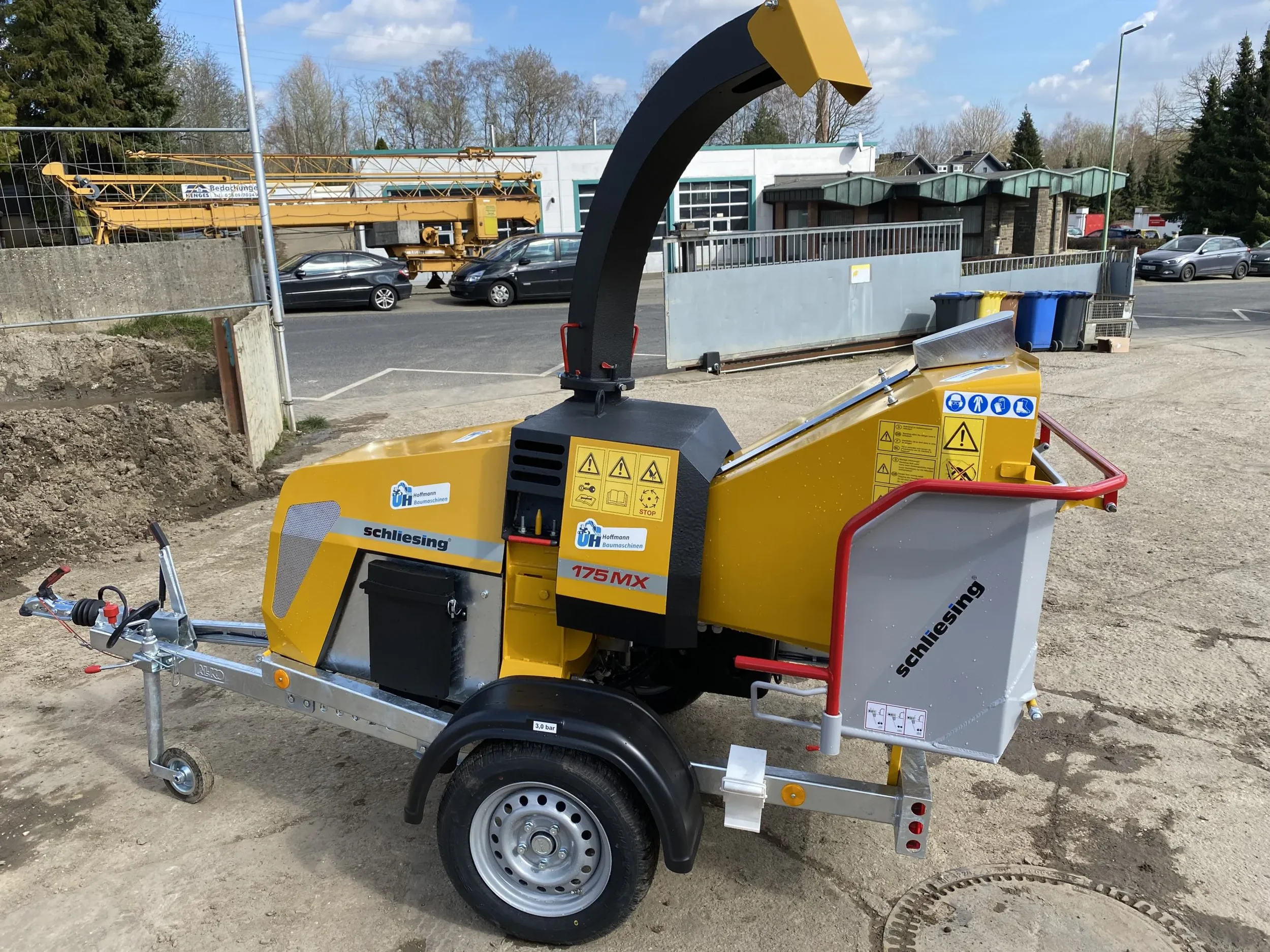 Seitenansicht eines gelben Holzhäckslers der Marke Schliesing auf einem Anhängerfahrgestell mit großem Einfülltrichter zur Miete für die effiziente Zerkleinerung von Ästen und Schnittgut.