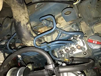 Detailansicht eines Hydraulik-Steuerblocks mit Schläuchen und Anschlüssen im Maschinenraum, geprüft während der Reparatur.