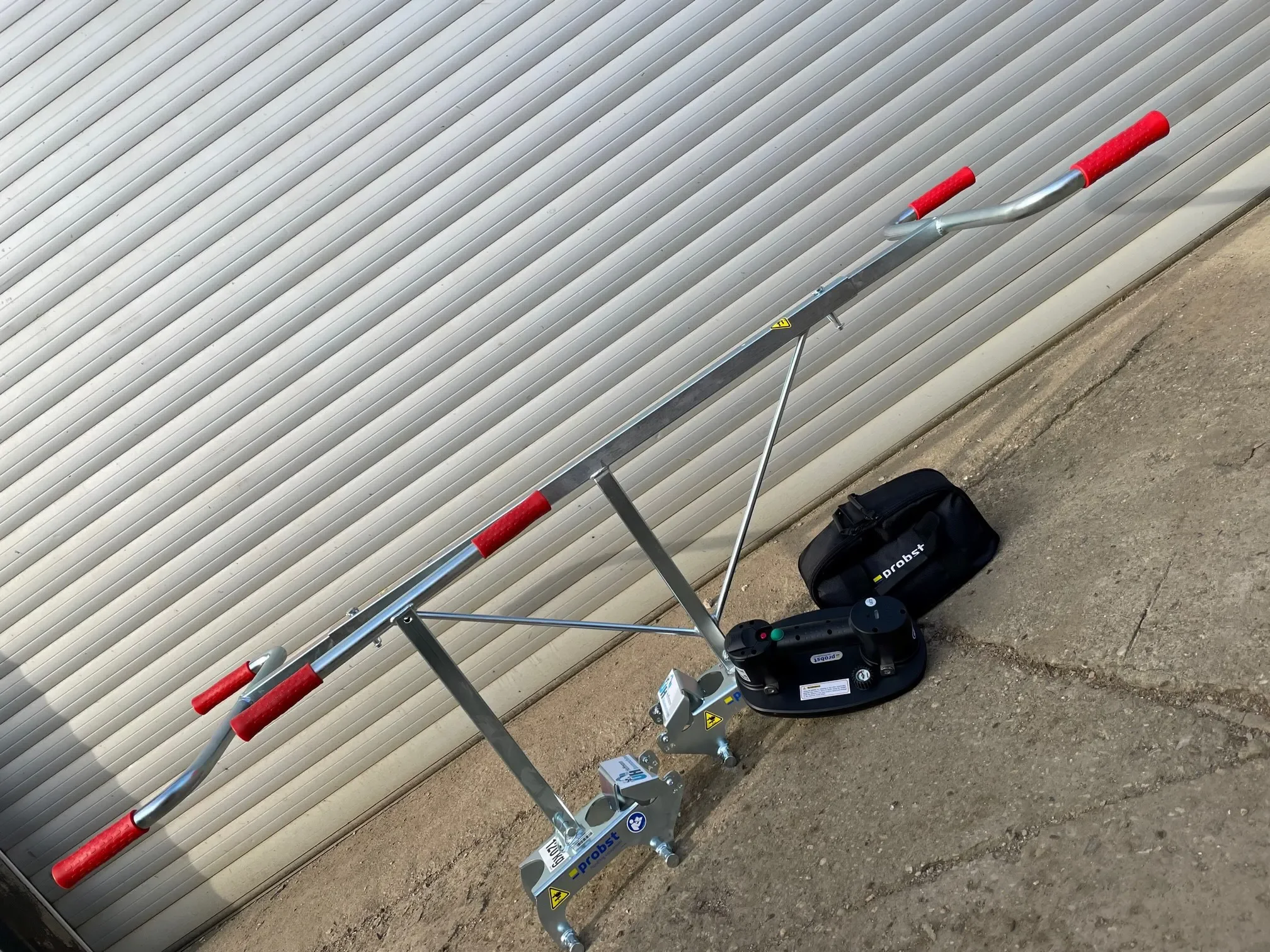 Elektrischer Vakuum-Plattenheber der Marke Probst mit langem Zweimann-Tragegriff und Akku-Saugeinheit zur Miete für das ergonomische und kraftsparende Heben und Verlegen von großen und schweren Steinplatten.