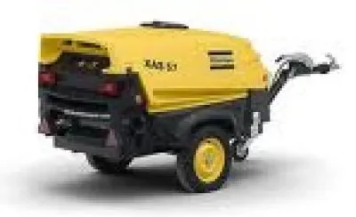 Gelber, fahrbarer Baukompressor der Marke Atlas Copco (Modell XAS 57) auf Einachs-Fahrgestell mit PKW-Anhängerkupplung zur Miete für die zuverlässige und mobile Druckluftversorgung von Druckluftwerkzeugen auf Baustellen.
