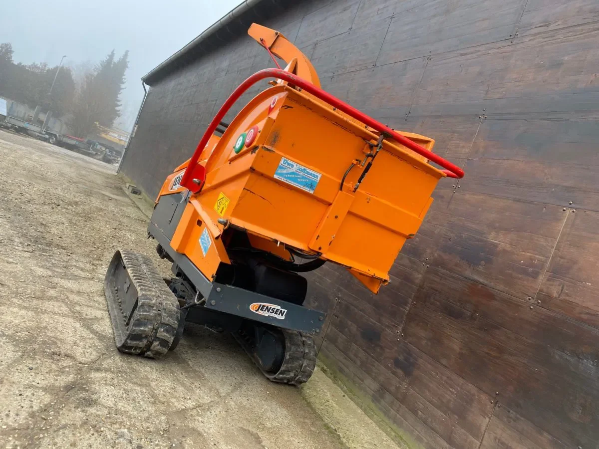 Orangefarbener Jensen A530XL Raupenhäcksler von hinten, mit Schutzbügel und Auswurfkanal, auf Betriebshof aufgenommen, Gebrauchtmaschine zum Verkauf.
