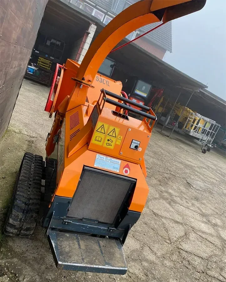 Frontansicht eines orangefarbenen Jensen A530XL Raupenhäckslers mit Einfülltrichter, Schutzbügel und Warnaufklebern auf dem Betriebshof, Gebrauchtmaschine zum Verkauf.