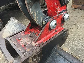 Nahaufnahme der Schnellwechsler-Aufnahme am Baggerlöffel mit Bolzen und Verschleißspuren, geprüft bei Reparaturarbeiten.