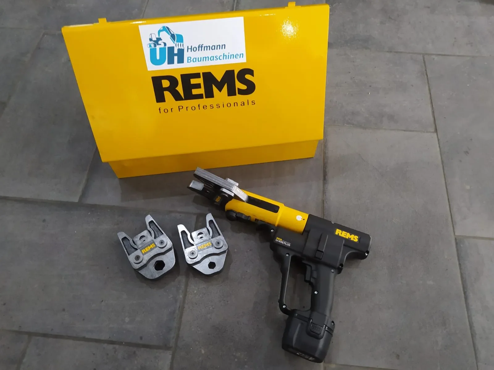 Professionelle, akkubetriebene Radialpresse (Presszange/Rohrpresse) der Marke REMS in Schwarz und Gelb mit zwei auswechselbaren Pressbacken, leistungsstarkem Akku und originalem gelbem Transportkoffer