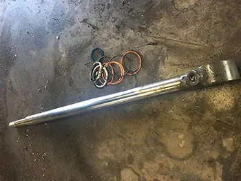 Ausgebauter Hydraulikkolben mit Dichtungsringen auf Werkstattboden, vorbereitet für Wartung und Reparatur.