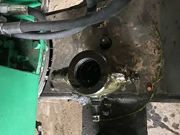 Geöffnetes Hydraulikgehäuse mit sichtbarem Zylinderinnenraum und angeschlossenen Leitungen, aufgenommen während der Reparatur in der Werkstatt.