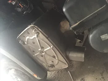 Maschinenmotor mit Metallabdeckung und angeschlossenen Leitungen in einer Werkstatt, während der Reparaturarbeiten.