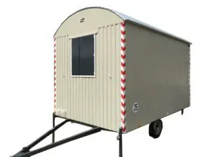 Heller einachsiger Bauwagen mit Fenster und rot-weißen Warnstreifen zur Miete als mobiler Aufenthaltsraum für Baustellen.