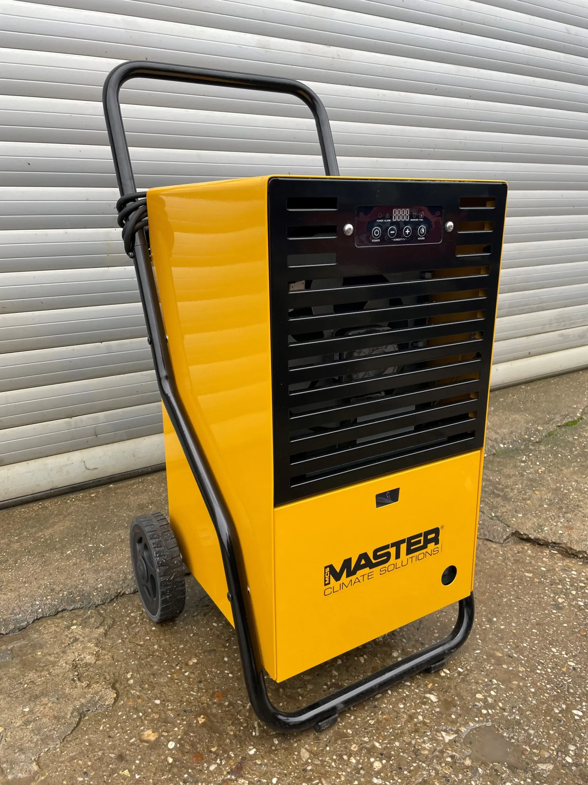 Gelber, fahrbarer Kondensationstrockner (Bautrockner) der Marke Master im robusten Metallgehäuse mit schwarzem Frontgitter, Transportgriff, großen Rädern.