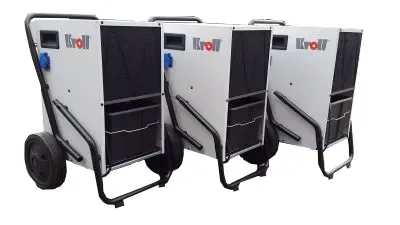 Drei fahrbare Kondensationstrockner (Bautrockner) der Marke Kroll im robusten Gehäuse mit Transportgriff, großen Rädern und integriertem Wasserbehälter zur Miete für die effiziente Bautrocknung, Entfeuchtung und Wasserschadensanierung in Gebäuden.