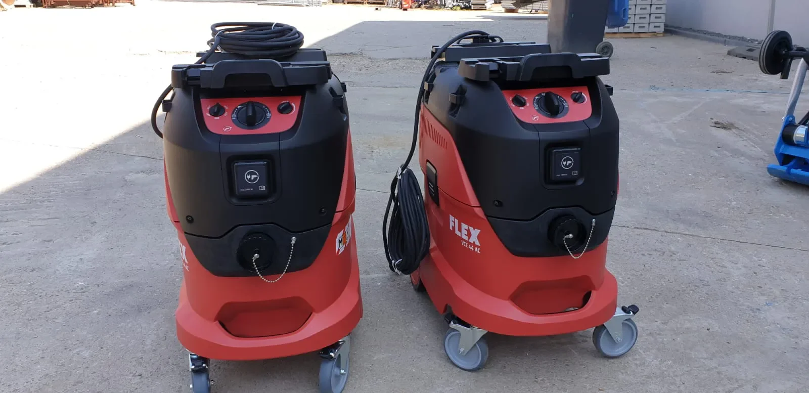 Zwei fahrbare, rot-schwarze Industriestaubsauger der Marke Flex mit integrierter Gerätesteckdose zur Miete für die professionelle Nass- und Trockenabsaugung sowie die direkte Staubabsaugung an Elektrowerkzeugen auf Baustellen und in Werkstätten.