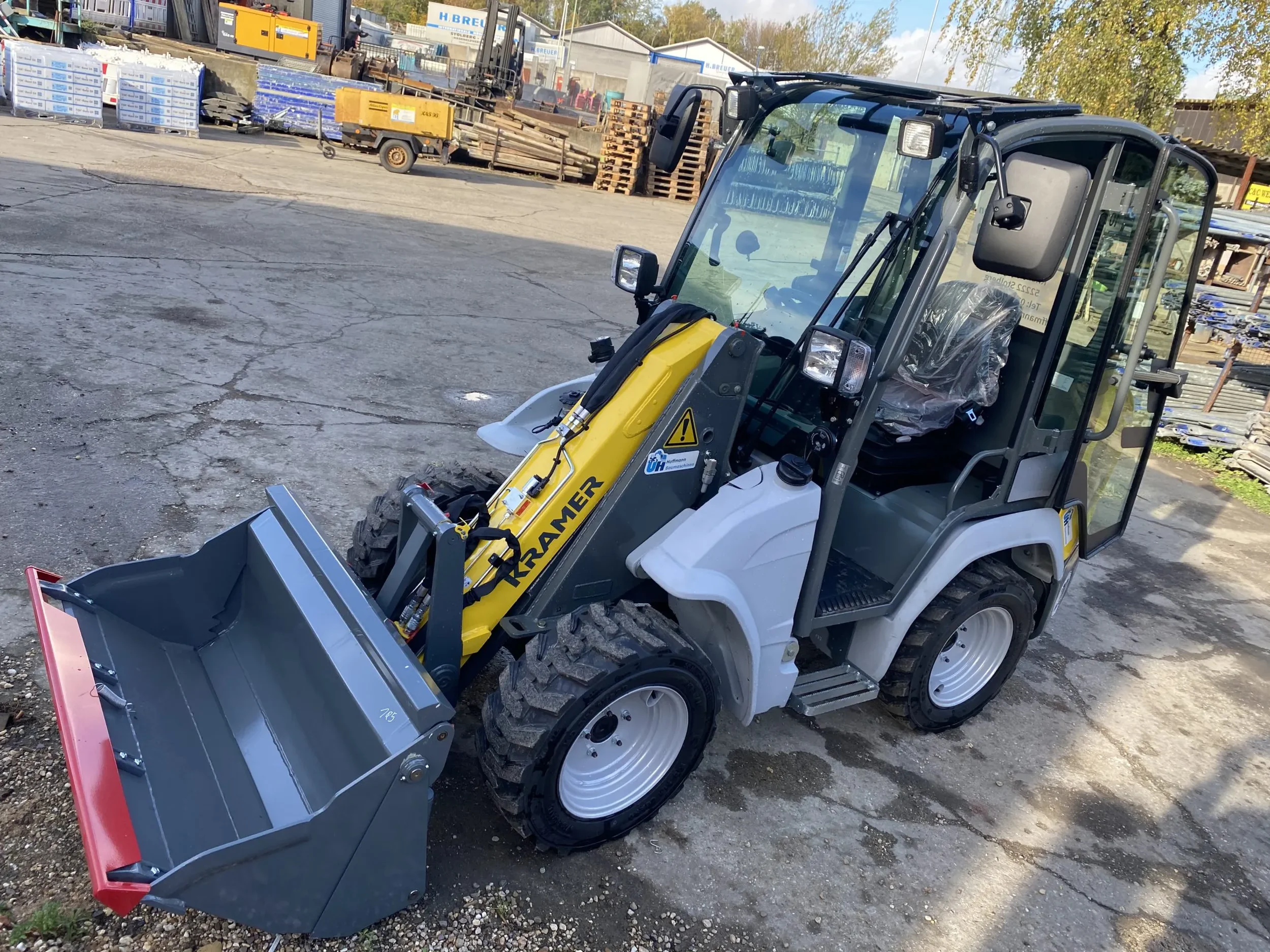 Kompakter, gelb-grauer Radlader der Marke Kramer (Modell 5035) mit geschlossener Kabine, Allradlenkung und breiter Ladeschaufel zur Miete für wendige und effiziente Lade.