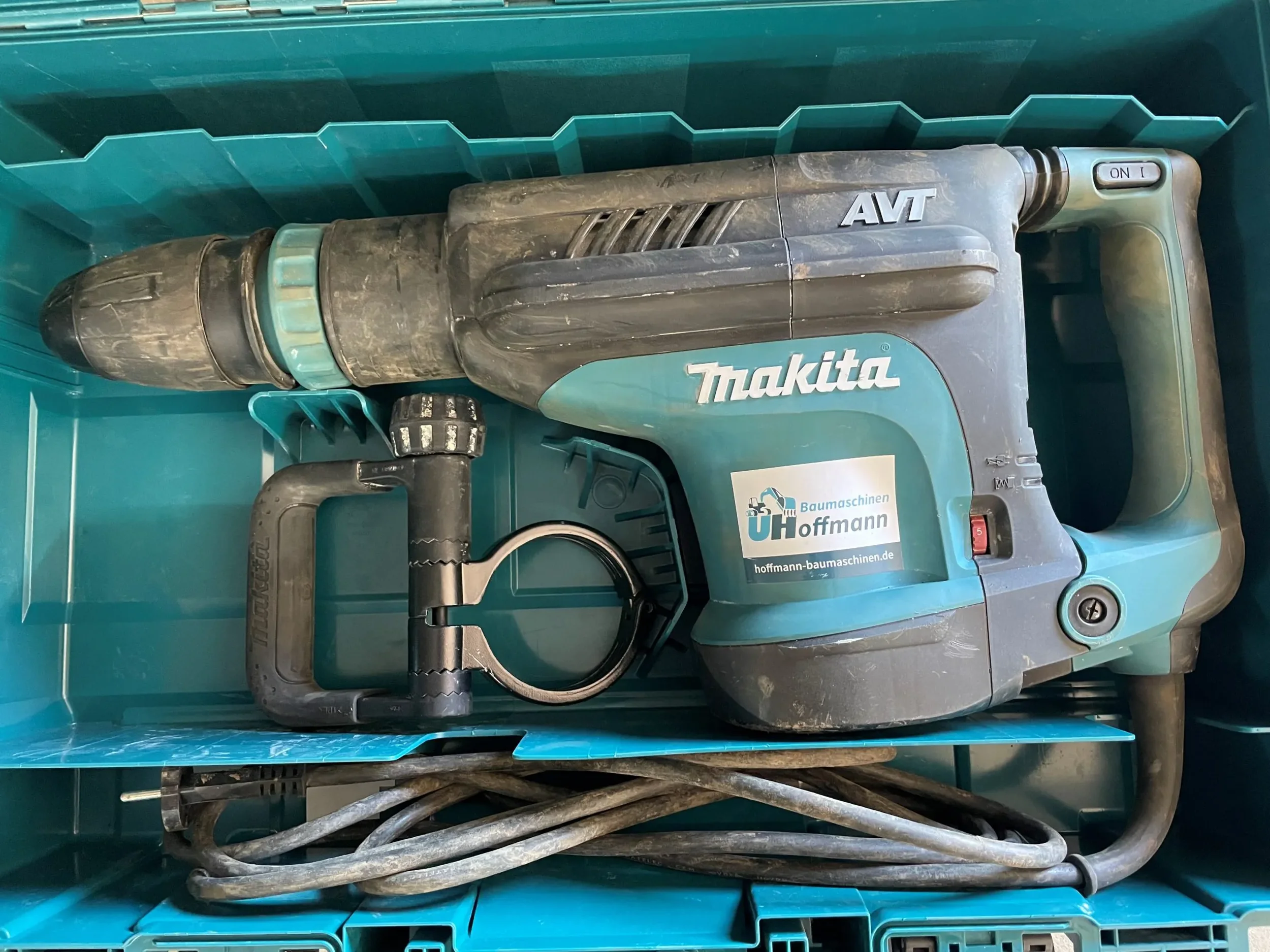 Türkis-schwarzer elektrischer Abbruchhammer der Marke Makita im Transportkoffer zur Miete für Stemm- und Abbrucharbeiten.