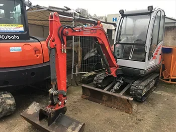 Zwei Minibagger auf dem Betriebshof, einer mit angebautem Löffel, aufgenommen im Rahmen von Service- und Reparaturarbeiten.