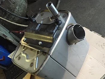 Ausgebautes Motorteil mit Metallgehäuse und Anschlussstutzen auf der Werkbank, vorbereitet für Reparatur und Prüfung.