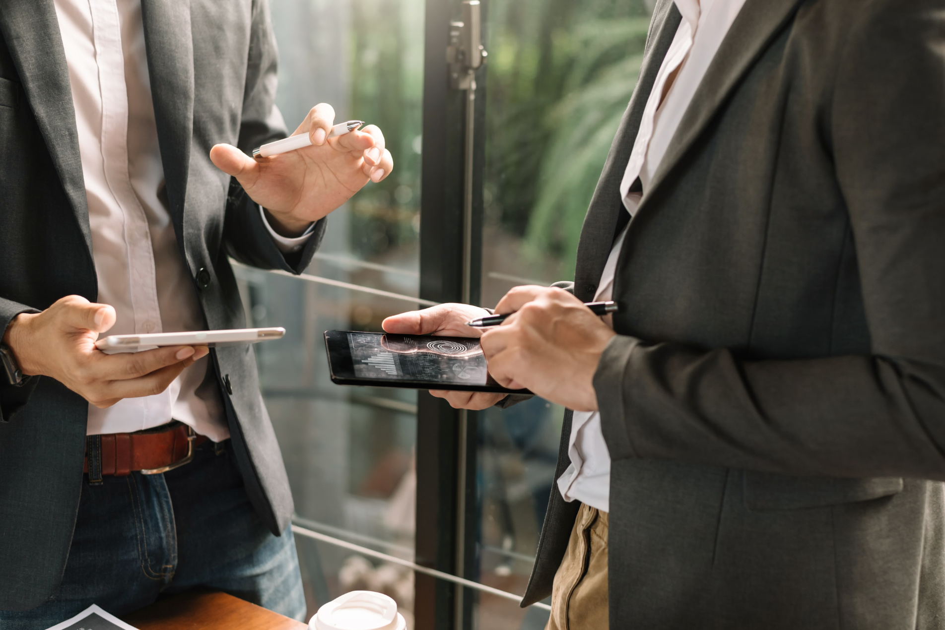 Manager standing in an office, holding an iPad and reviewing documents.