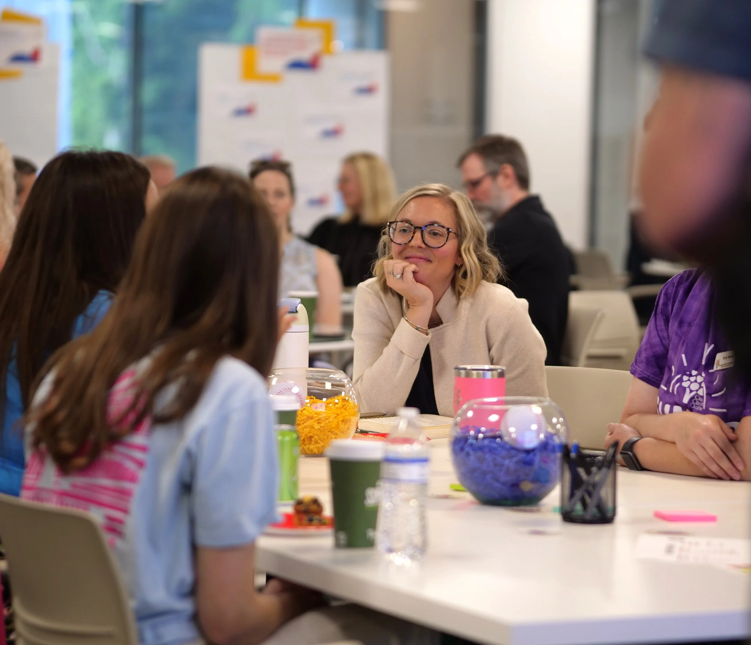 Jessica Whatley listening during a workshop discussion, seated at a table with participants.
