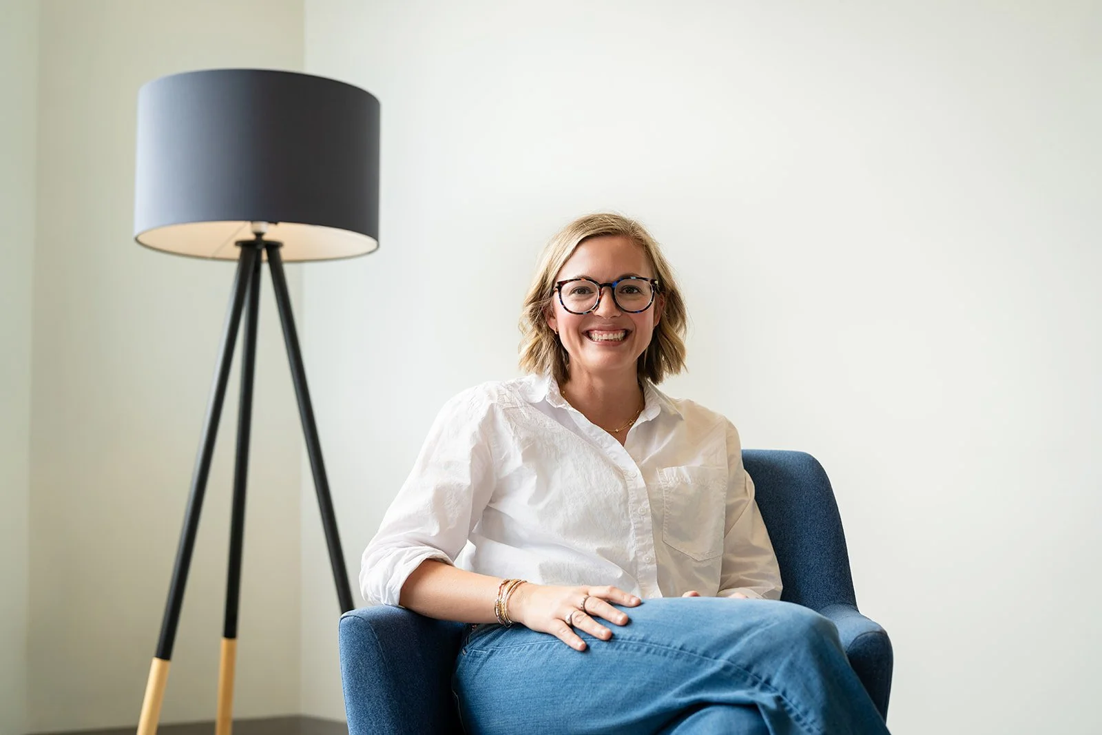 Jessica Whatley, founder of The Efficiency Choice, sitting in a blue armchair and smiling.