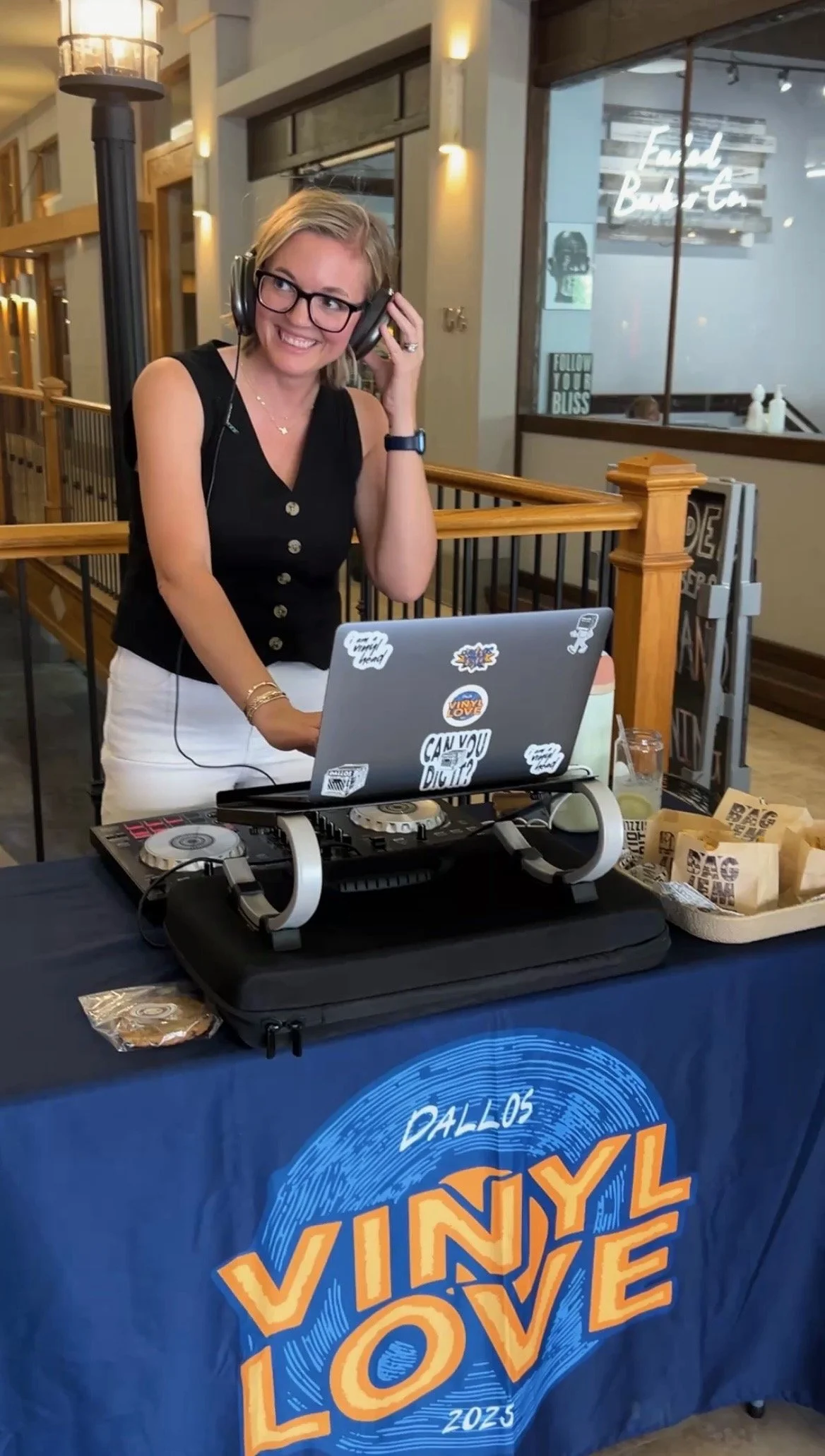 Jessica Whatley DJing a live event, headphones on and laptop set up at the booth