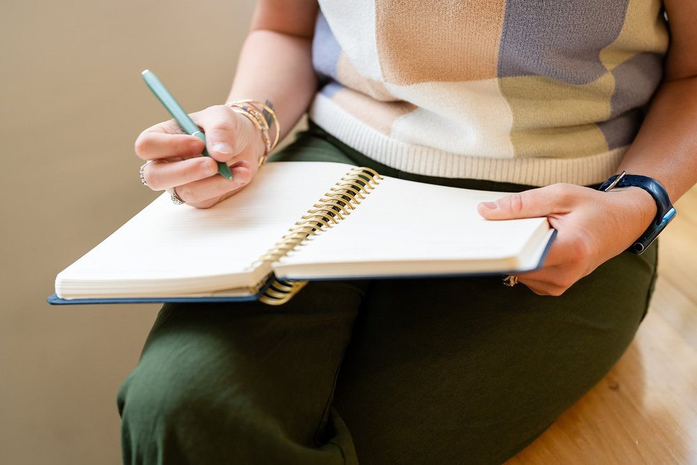 A woman sitting with her planner open, planning her week
