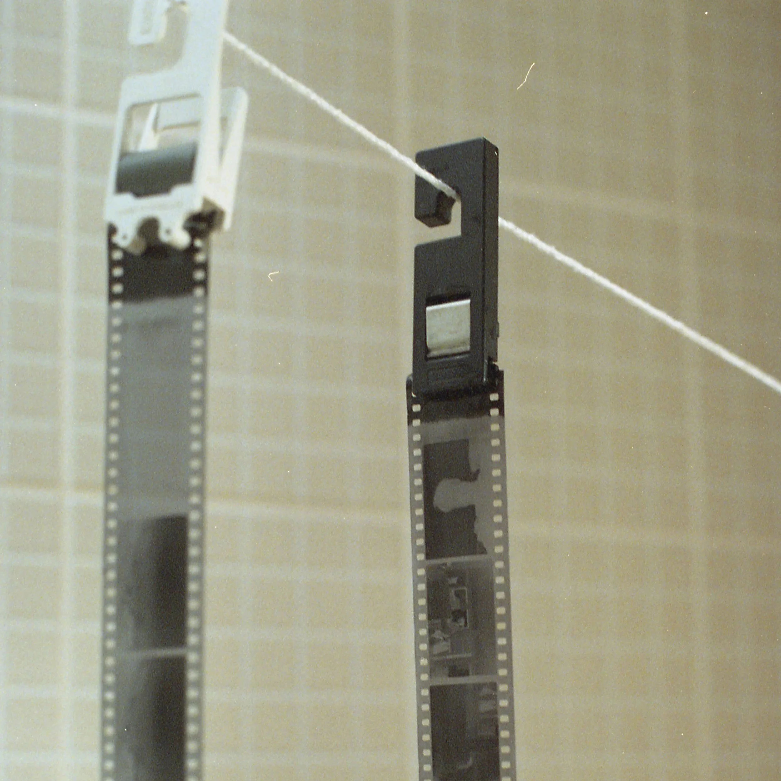 Someone holding a strip of film in a bathroom with gray tiled wall.